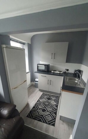 A compact kitchen with a refrigerator, microwave, and sink. - Unique 2 Floor Apartment in Manchester. Private Cinema! (Manchester)