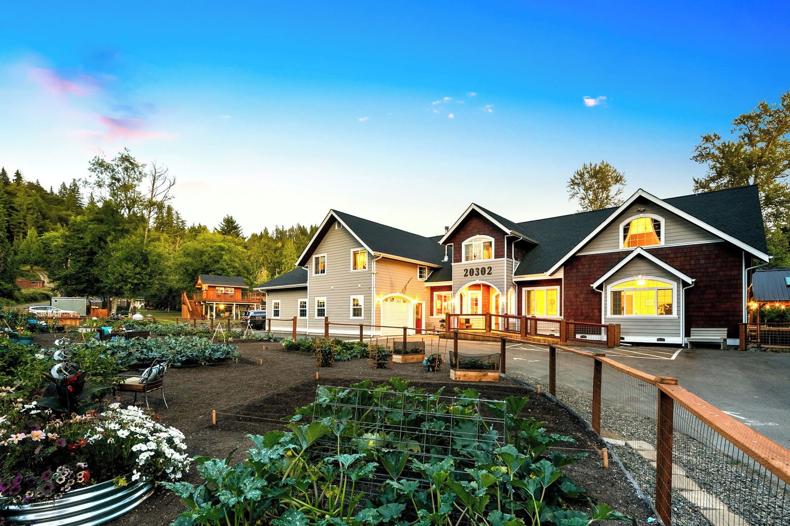 A residential property with a well-maintained garden, a fenced driveway, and a variety of plants.
