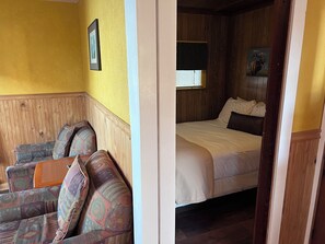 A room with a bed, a sofa, and a window with blinds.