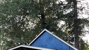 Un petit bâtiment bleu avec un porche, une porte et une fenêtre.