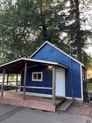 A small blue building with a porch, a door, and a window.
