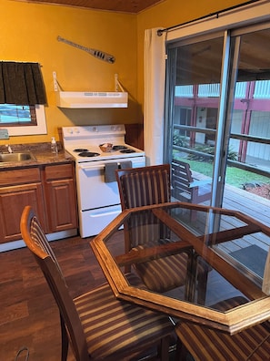 Une cuisine équipée d’une cuisinière, d’un évier et d’un coin repas avec une table et des chaises en verre.