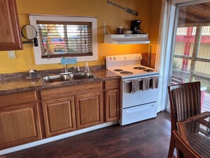 A kitchen with wooden cabinets, a white stove, and a window with blinds.