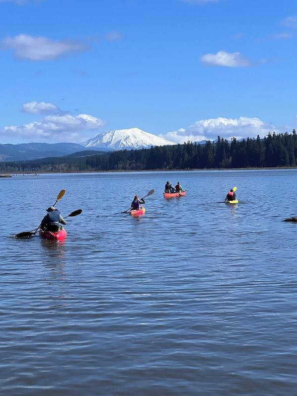 A group of kayakers on a calm lake with a snow-capped mountain in the background.