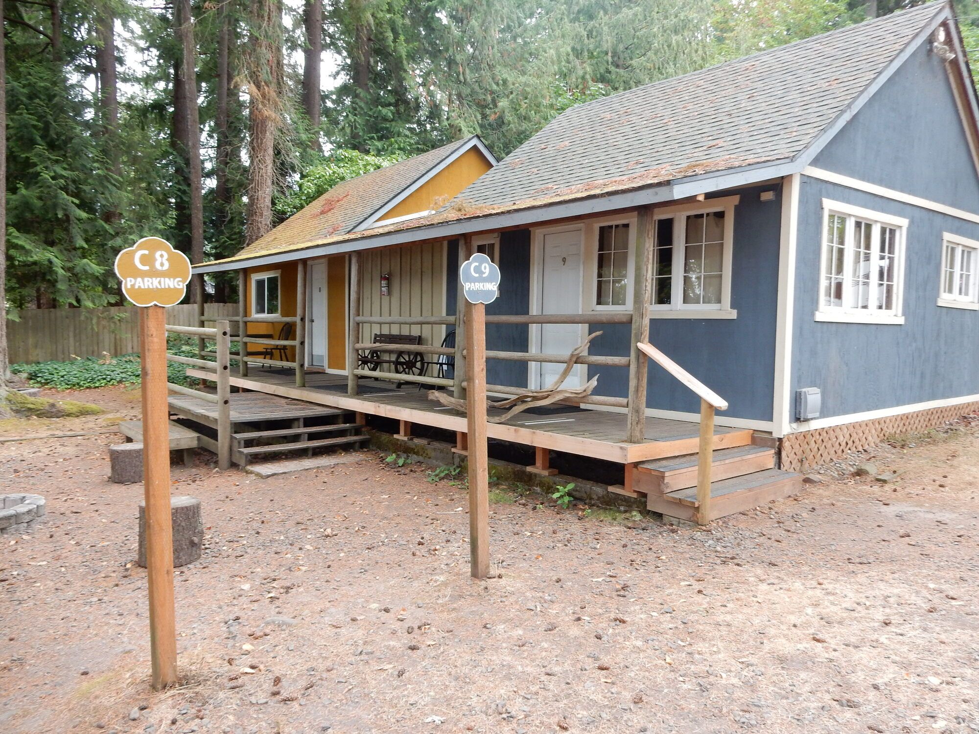 A rustic cabin with a porch, wooden steps, and a gravel ground.
