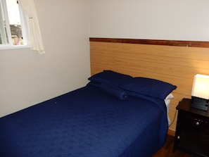 A single bed with a wooden headboard and a blue bedspread.