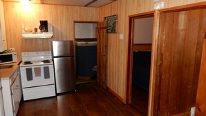 Cocina compacta con refrigerador, estufa, microondas y gabinetes de madera.