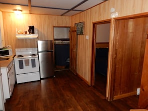 A compact kitchen with a refrigerator, stove, microwave, and wooden cabinets. - Cabin 9: A Comfortable Two-Bedroom Cabin by Silver Lake (Silver Lake)