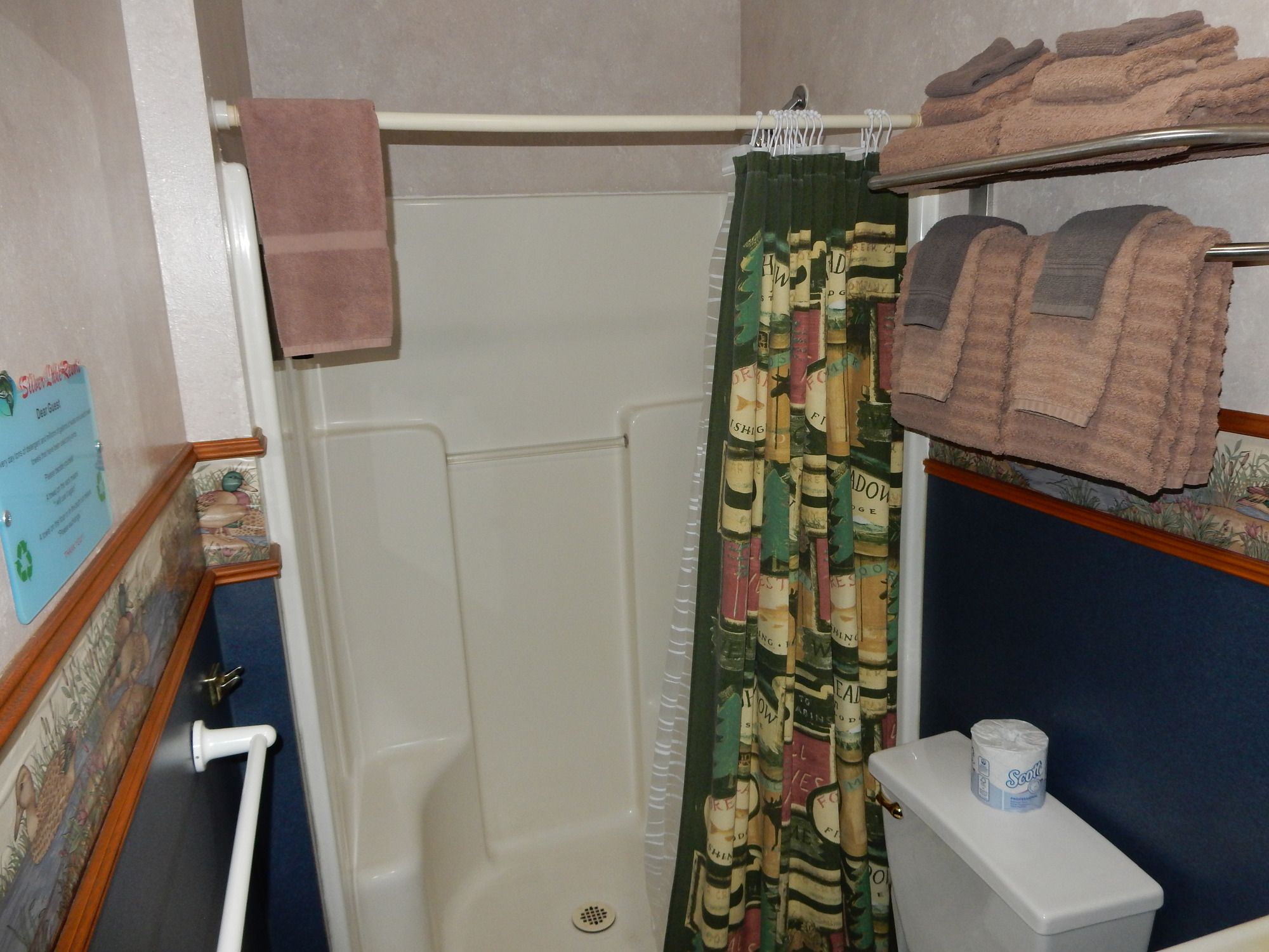 A bathroom with a shower curtain, a toilet, and a towel rack with towels.