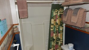 Un baño con cortina de ducha, inodoro y toallero con toallas.