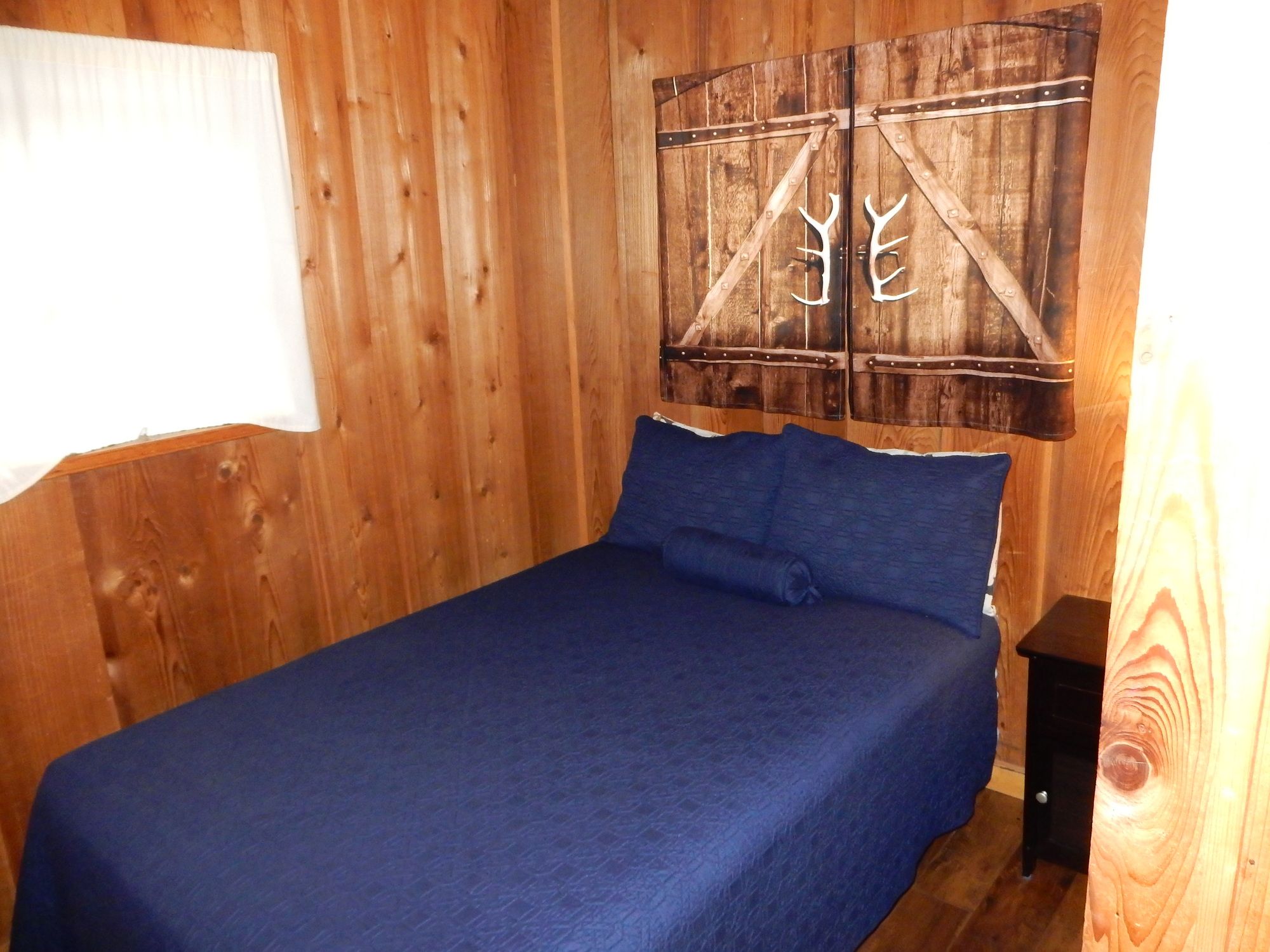 A wooden room with a bed, a wall-mounted decoration, and a small table.