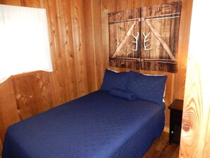A wooden room with a bed, a wall-mounted decoration, and a small table. - Cabin 9: A Comfortable Two-Bedroom Cabin by Silver Lake (Silver Lake)