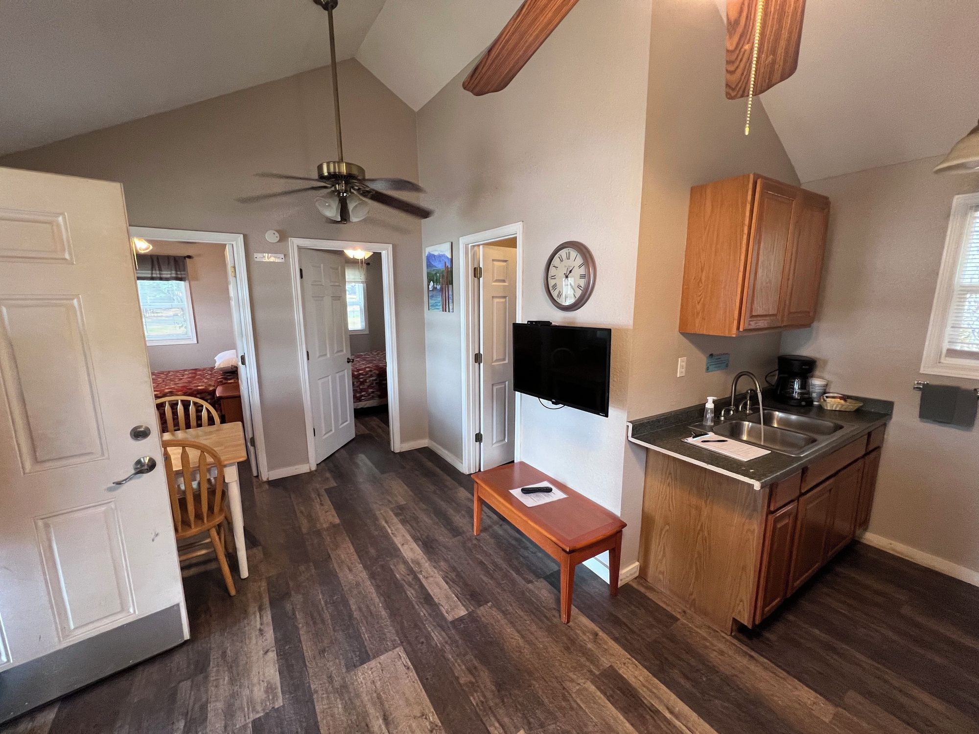 A compact kitchen with a dining area, a ceiling fan, and a clock on the wall.