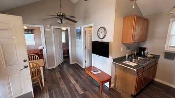 A compact kitchen with a dining area, a ceiling fan, and a clock on the wall.