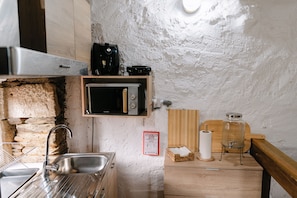 A compact kitchen with a built-in microwave, a coffee maker, and a sink.