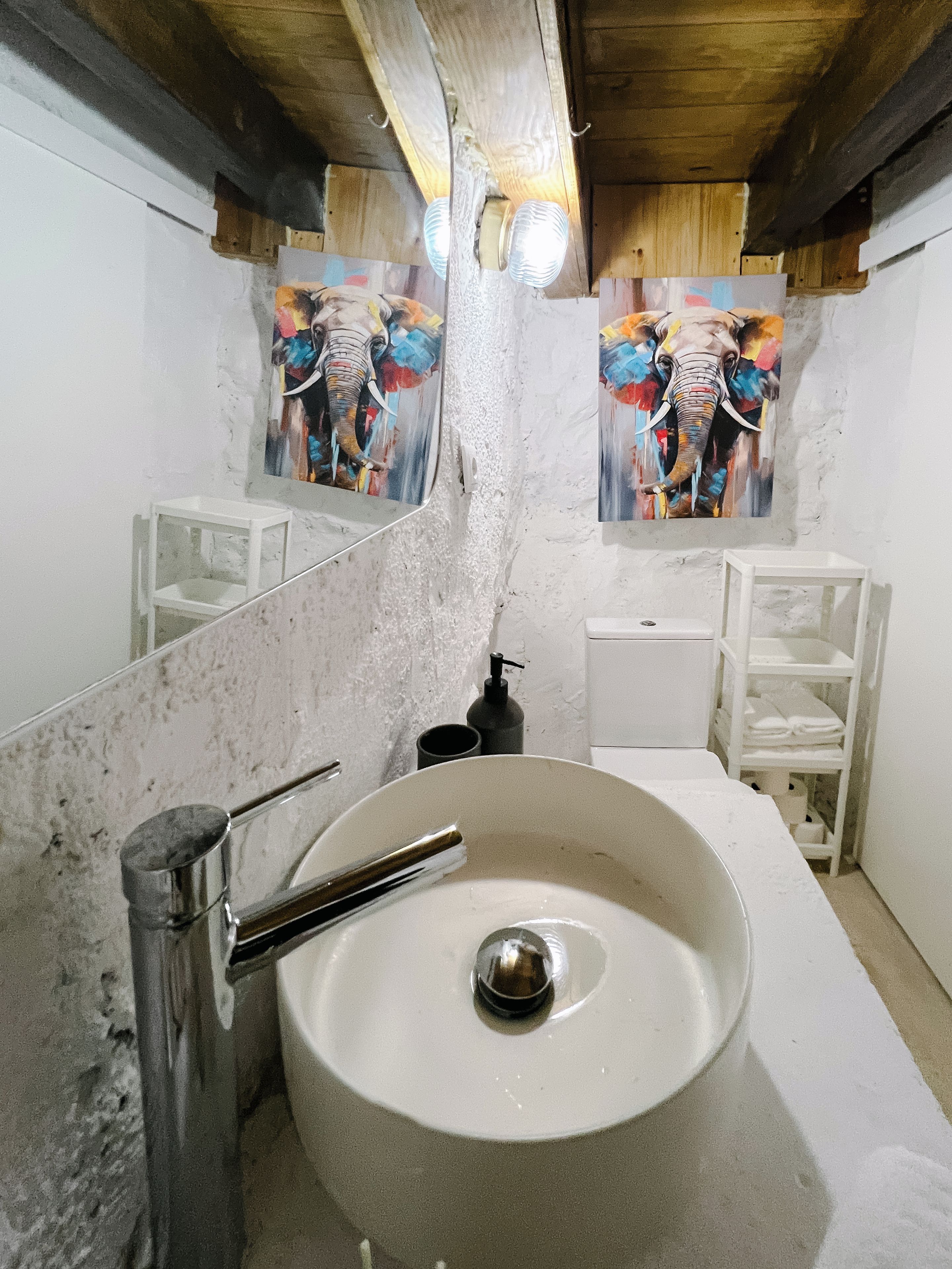 A bathroom with a large mirror, a round sink, and two wall-mounted light fixtures.
