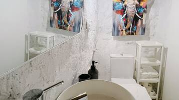 A bathroom with a large mirror, a round sink, and two wall-mounted light fixtures.