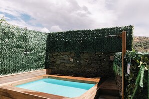A swimming pool with a stone wall and a hedge.