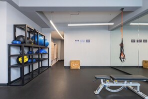 Ein Fitnessraum mit Trainingsgeräten, einer Bank und einem Spiegel.