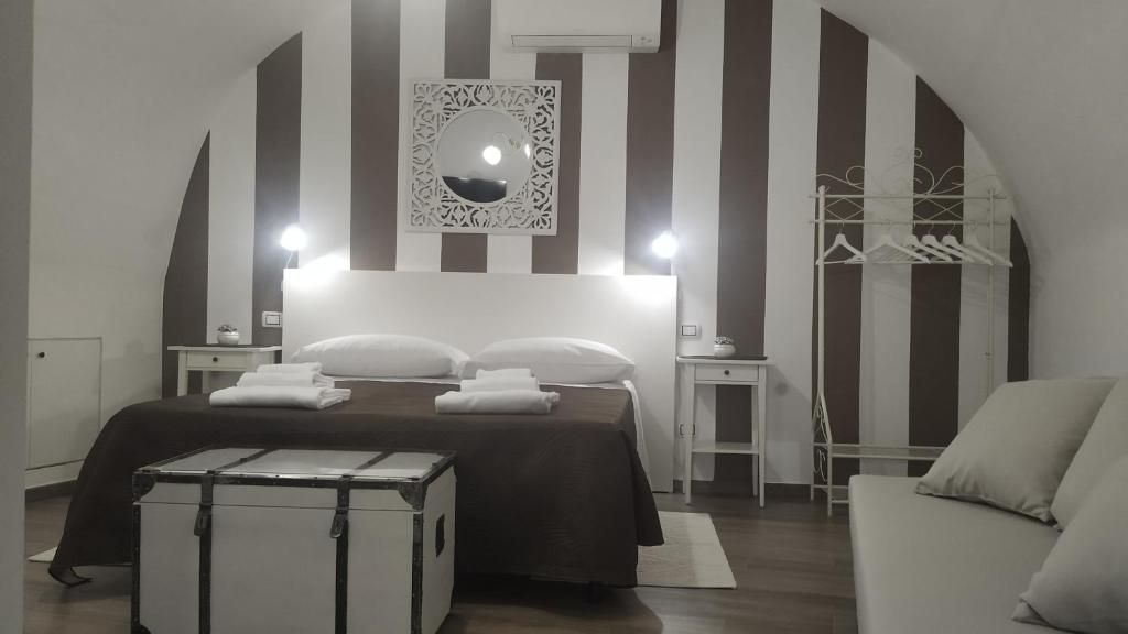 A bedroom with a bed, bedside tables, a mirror, a hanging clothes rack, and a suitcase.