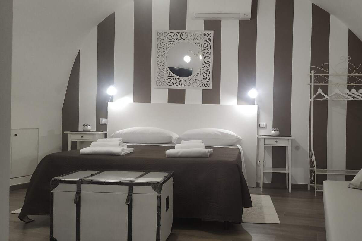 A hotel room with a bed, a wardrobe, a mirror, and a suitcase.