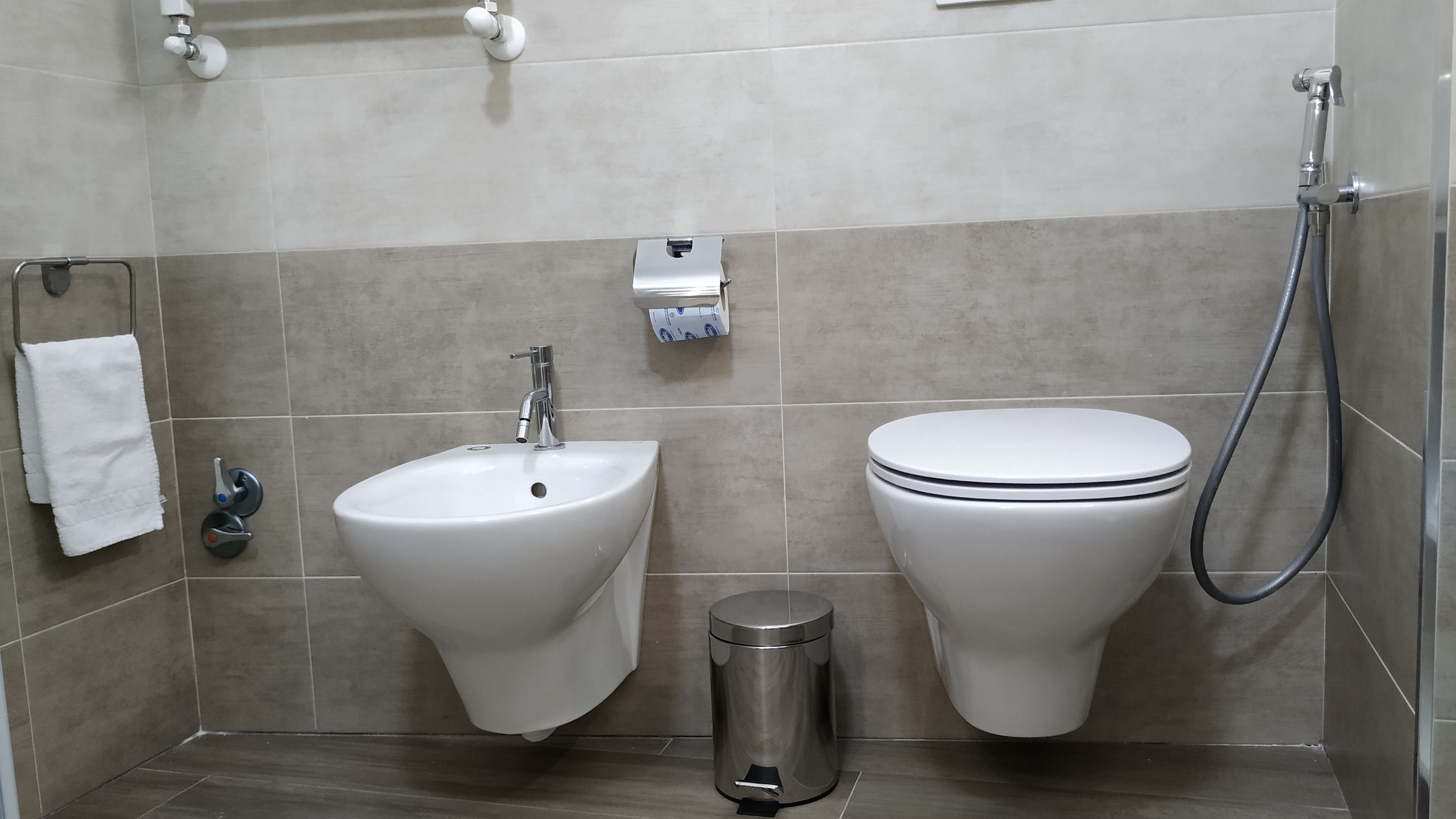 A bathroom with a sink, toilet, and a trash bin.
