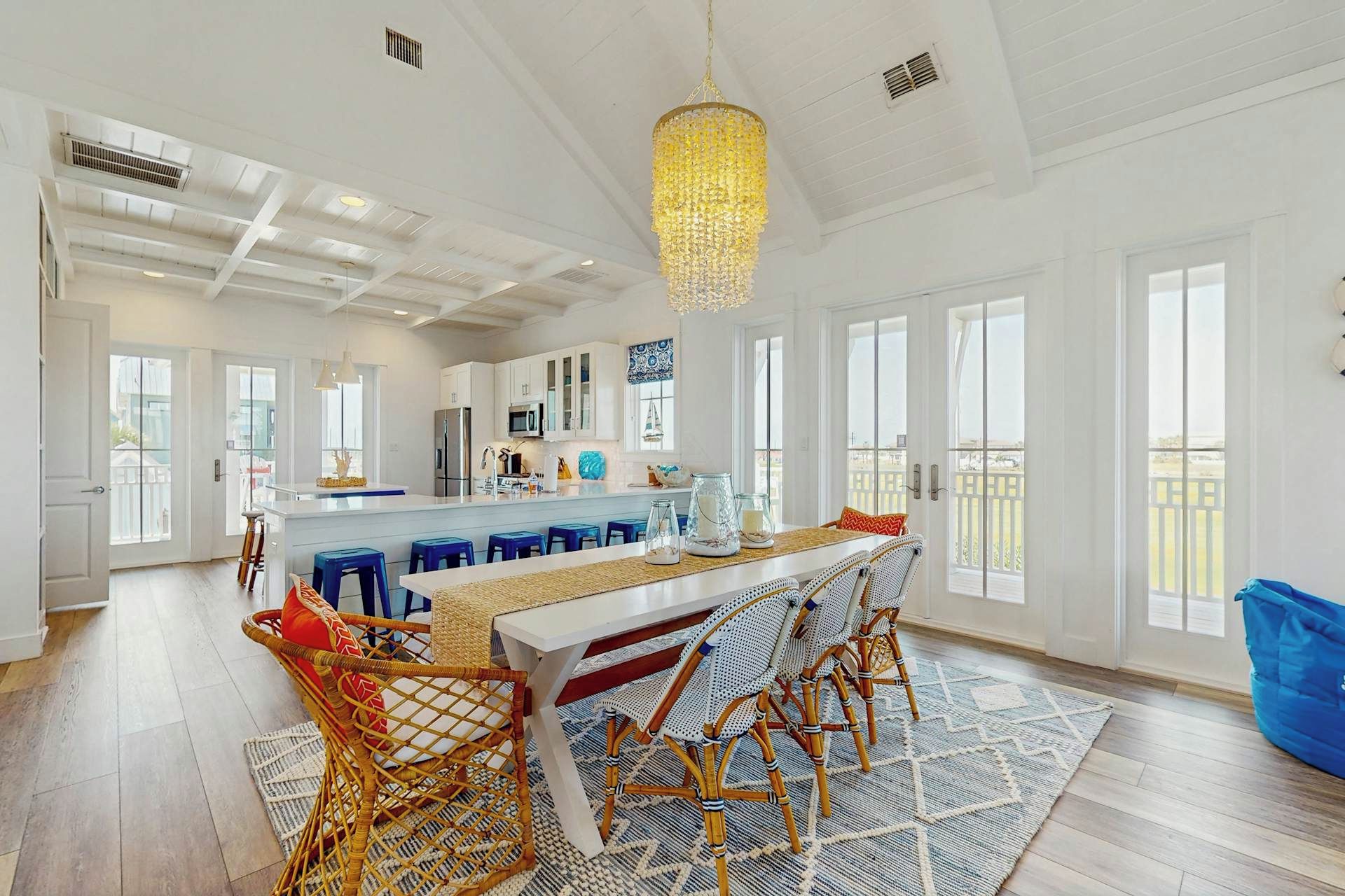 A spacious kitchen with a central island, white cabinetry, and a large chandelier.