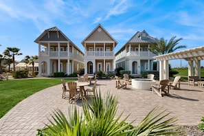 A large, two-story house with a covered patio area featuring outdoor furniture and a fire pit. - Palmilla Beach Resort-102 Agave Lane (Port Aransas)