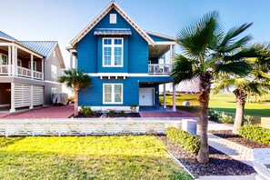 A two-story house with a balcony, a covered porch, and a well-maintained lawn. - Palmilla Beach Resort-103 Salt Grass (Port Aransas)