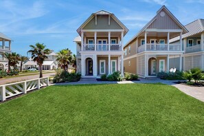 A two-story residential building with a front porch, a driveway, and a well-maintained lawn. - Palmilla Beach Resort-104 Agave Lane (Port Aransas)