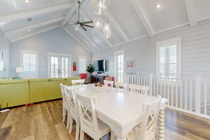 A spacious living area with a white dining table, white chairs, a green sofa, and a ceiling fan. - Palmilla Beach Resort-104 Agave Lane (Port Aransas)