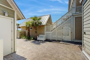 A residential property with a paved driveway, a staircase leading to a deck, and a palm tree. - Palmilla Beach Resort-104 Agave Lane (Port Aransas)