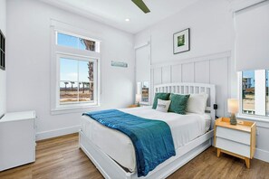 A bedroom with a bed, a nightstand, a window with a view, and a wall-mounted picture. - Palmilla Beach Resort-106 Sea Whip Lane (Port Aransas)