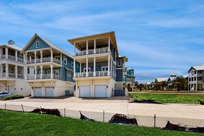 A multi-story residential building with a balcony, garage doors, and a well-maintained lawn. - Palmilla Beach Resort-114 Cattail Street (Port Aransas)
