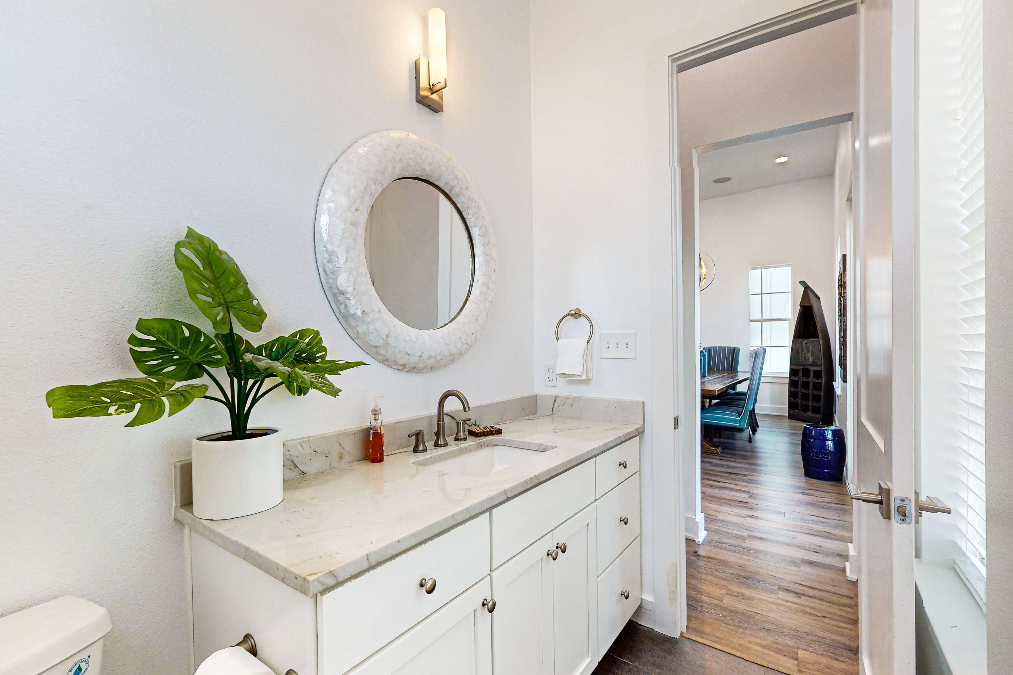 A bathroom with a white sink, a large mirror, and a potted plant.