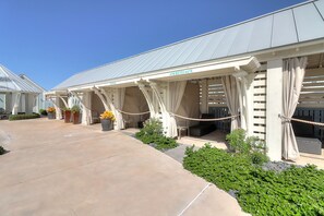 Un espacio al aire libre cubierto con una pérgola, plantas en macetas y un cielo azul despejado.