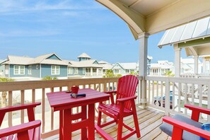 Une terrasse en bois avec une table et des chaises, d’où l’on peut admirer une rangée de maisons aux toits bleus.