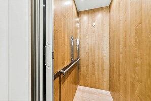 A narrow elevator with wooden walls and a metal handrail. - Palmilla Beach Resort-120 Cattail Street (Port Aransas)