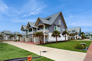 A modern residential building with a symmetrical design, multiple balconies, and a well-maintained lawn. - Palmilla Beach Resort-121 Wild Indigo (Port Aransas)
