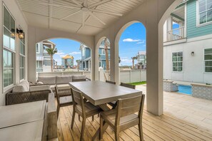 An outdoor patio with a table and chairs, a pool, and a view of neighboring houses. - Palmilla Beach Resort-127 Sweetbay Street (Port Aransas)