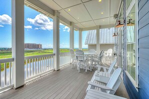 A covered outdoor area with a view of the ocean and a golf course, furnished with white chairs and a table. - Palmilla Beach Resort-128 Cattail Lane (Port Aransas)