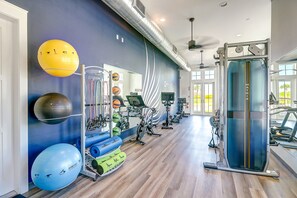 A modern gym with various exercise equipment, a large mirror, and a blue wall with a unique design. - Palmilla Beach Resort-131 Sabal Lane (Port Aransas)