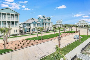 A residential area with multiple two-story houses, a well-maintained lawn, and a clear sky. - Palmilla Beach Resort-131 Wild Indigo Street (Port Aransas)