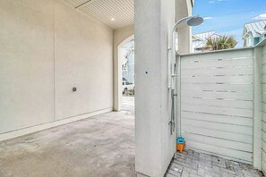 Ein eingezäunter Außenbereich mit Betonboden, einem Metallgitter und einer kleinen, orangefarbenen Mülltonne.