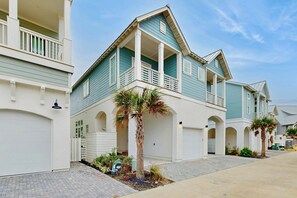 Ein zweigeschossiges Wohngebäude mit Balkon, Garage und befestigter Auffahrt.