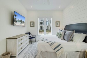 Ein Schlafzimmer mit einem Bett, einem Schminktisch, einem Sessel und einem Fernseher an der Wand.