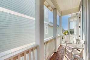 A covered porch with a wooden deck, white railings, and a view of neighboring houses. - Palmilla Beach Resort-133 Sunrise Avenue (Port Aransas)
