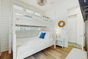A bunk bed with a white finish, a bedside table with a lamp, and a door with a circular mirror. - Palmilla Beach Resort-133 Sweetbay Street (Port Aransas)