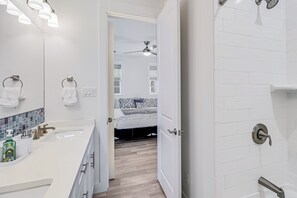 A modern bathroom with a white sink, a mirror, and a shower area. - Palmilla Beach Resort-135 Sunrise Avenue (Port Aransas)