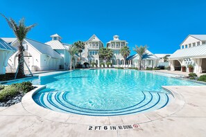 A swimming pool with a 2 ft 6 in no diving depth marker, surrounded by white buildings with balconies and palm trees. - Palmilla Beach Resort-135 Wild Indigo Street (Port Aransas)